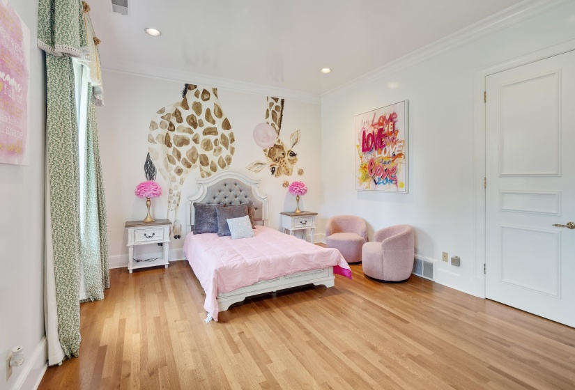 Spacious room featuring wood-finish flooring, recessed lighting, crown molding, and a paneled door