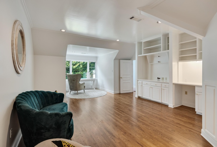 Room featuring hardwood flooring and white walls, with an integrated built-in desk and shelving unit
