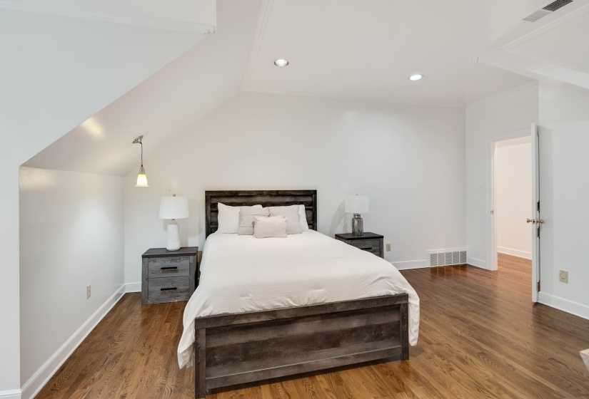 Hardwood flooring throughout featuring an angled ceiling, recessed lighting, and white baseboards