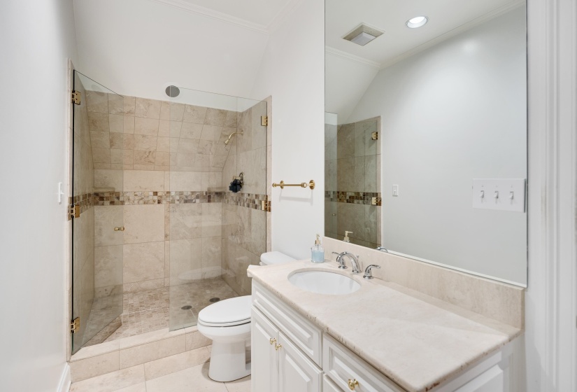 Bathroom featuring a glass-enclosed shower with tile surround and decorative accent band, a white vanity with an undermount sink, a light-toned countertop, and chrome fixtures