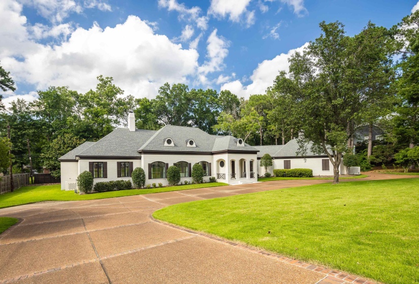 White stucco exterior featuring a gray shingle roof and a prominent portico entrance