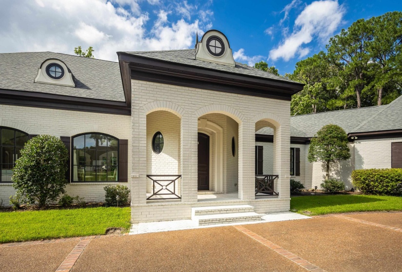 Elegant brick facade with dark trim, featuring an arched entryway and round dormer windows