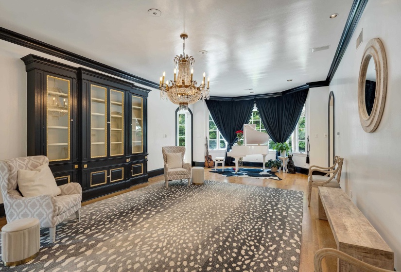 Spacious room featuring hardwood flooring, multiple large windows, and a built-in display cabinet with glass doors and gold accents