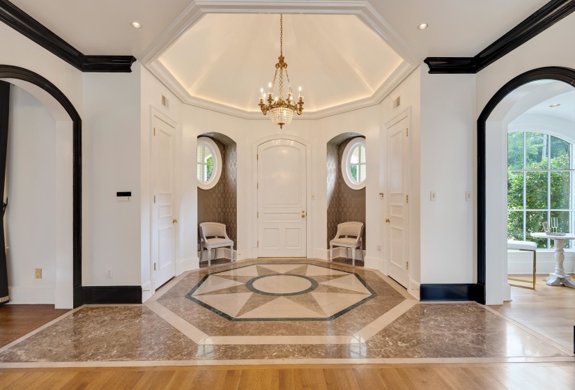 Grand entry foyer featuring an octagon-patterned tile floor, a tray ceiling with recessed lighting, and a prominent chandelier