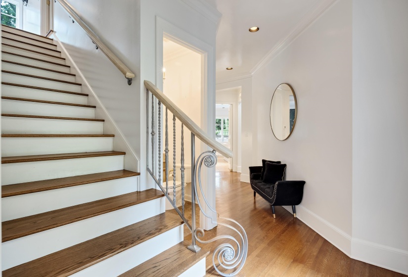 Grand staircase featuring wood-finish treads, white risers, and an ornate metal baluster