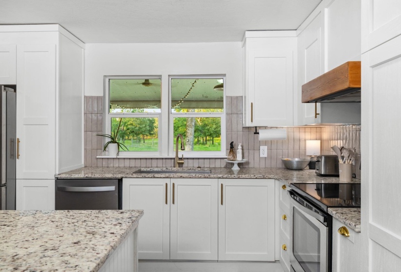 Modern kitchen featuring white shaker cabinetry and light-colored granite countertops