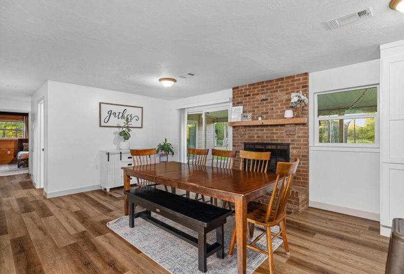 Dining area featuring wood-finish flooring, a brick fireplace with a wood mantle, and sliding glass door access