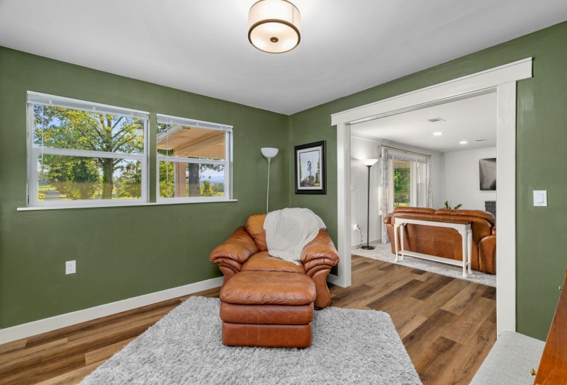 Room featuring two large windows, wood-finish flooring, and a cased opening leading to an additional area