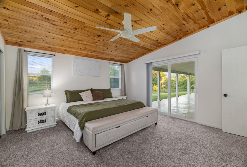 Spacious room featuring a wood-finish vaulted ceiling, ceiling fan, and plush gray carpeting