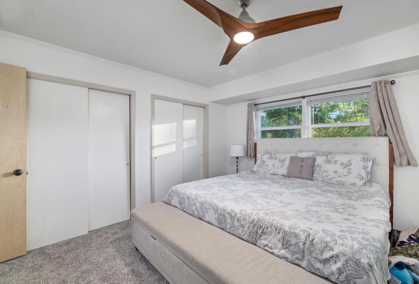 Bedroom featuring light gray carpet flooring, a modern ceiling fan with wood-finish blades, and white walls