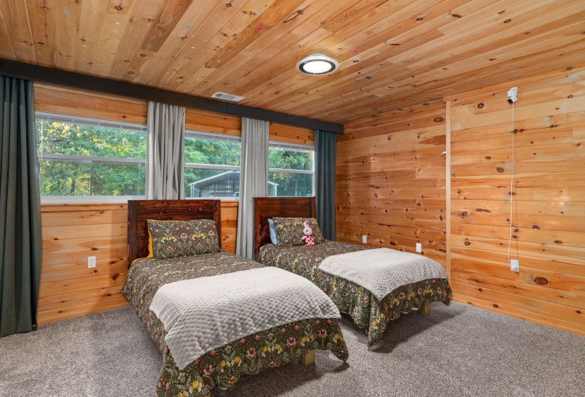 Interior room featuring wood-plank walls and ceiling, gray carpeting, and multiple windows with exterior views