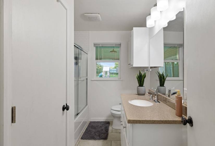 Bathroom vanity with a light speckled countertop, undermount sink, and chrome faucet