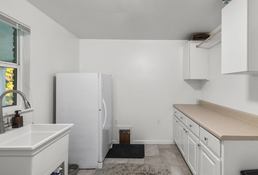 Utility sink with gooseneck faucet, white cabinetry, integrated countertop, and tiled flooring