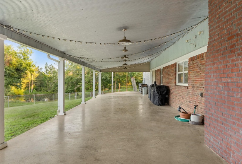 Expansive covered patio with concrete flooring, brick exterior wall, and multiple support columns