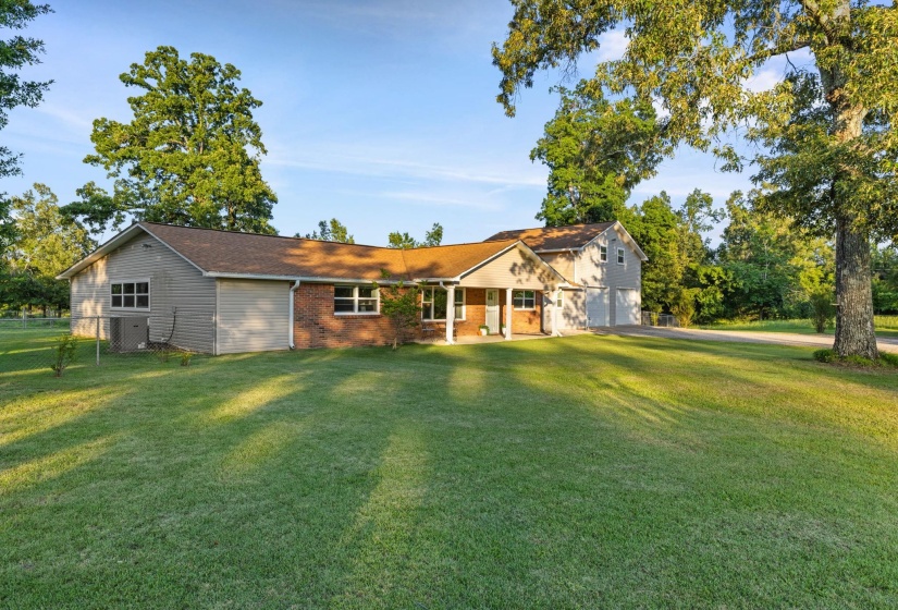 Expansive front yard with a brick and siding exterior, a covered entryway, and two attached garages