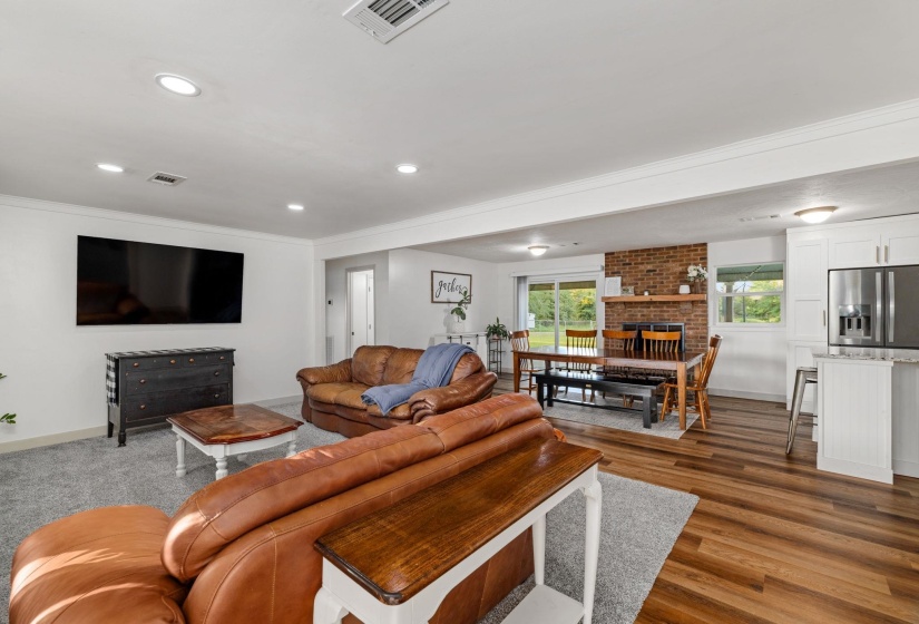 Living area showcasing recessed lighting, light gray carpeting, and a wall-mounted display