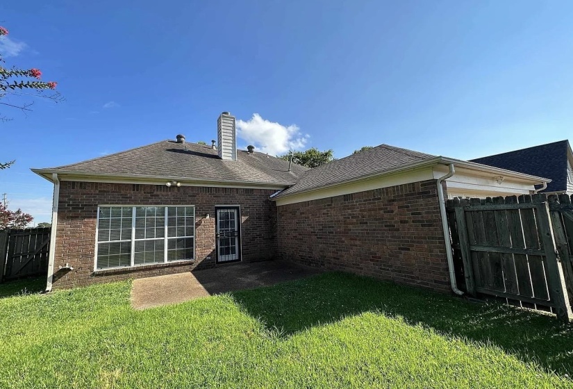 Brick exterior with a gabled roofline, featuring a concrete patio and a security screen door