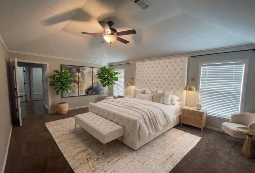 Spacious bedroom featuring vaulted ceilings, a ceiling fan with light fixture, carpet flooring, and a large window with blinds