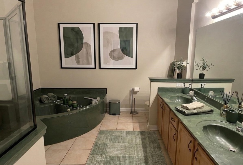 Bathroom featuring a corner soaking tub and a double vanity with integrated green sinks and countertops