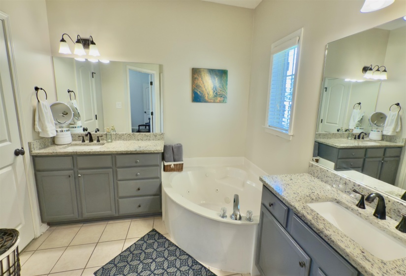 Full bathroom with tile patterned flooring, a tub with jets, and two vanities