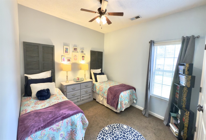 Bedroom featuring multiple windows, dark colored carpet, and ceiling fan