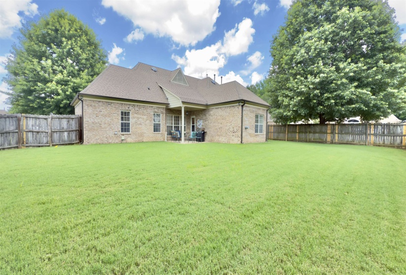 Rear view of property featuring a fenced backyard, brick siding, and roof with shingles