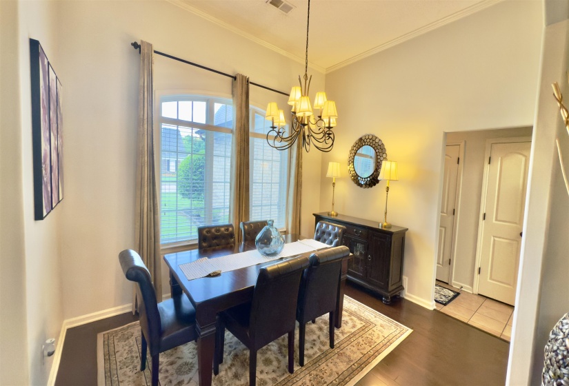 Dining space with ornamental molding, a chandelier, and dark wood finished floors