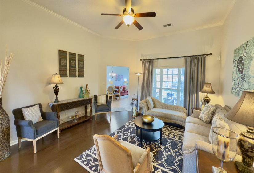 Living room featuring a ceiling fan, wood finished floors, and crown molding