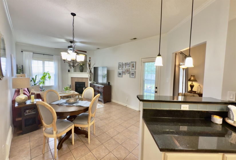 Dining space with a chandelier, light tile patterned floors, a tiled fireplace, and ornamental molding