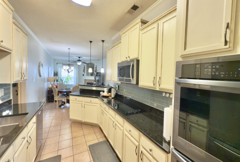 Kitchen with stainless steel appliances, cream cabinetry, backsplash, light tile patterned flooring, and a ceiling fan