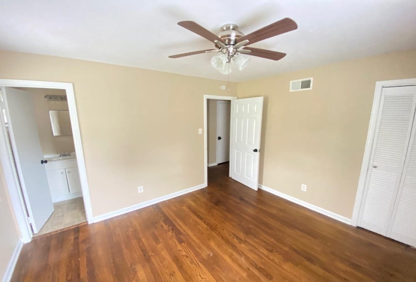 Room featuring wood-finish flooring, a ceiling fan with light fixture, neutral wall paint, and white trim