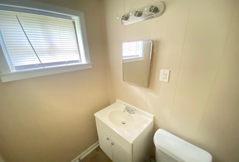 Bathroom featuring a single-sink vanity with white cabinetry, a wall-mounted mirror, and a three-light fixture