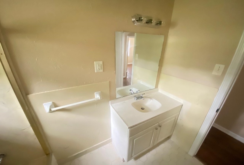 Bathroom vanity with an integrated sink and base cabinetry, featuring a wall-mounted mirror and chrome faucet
