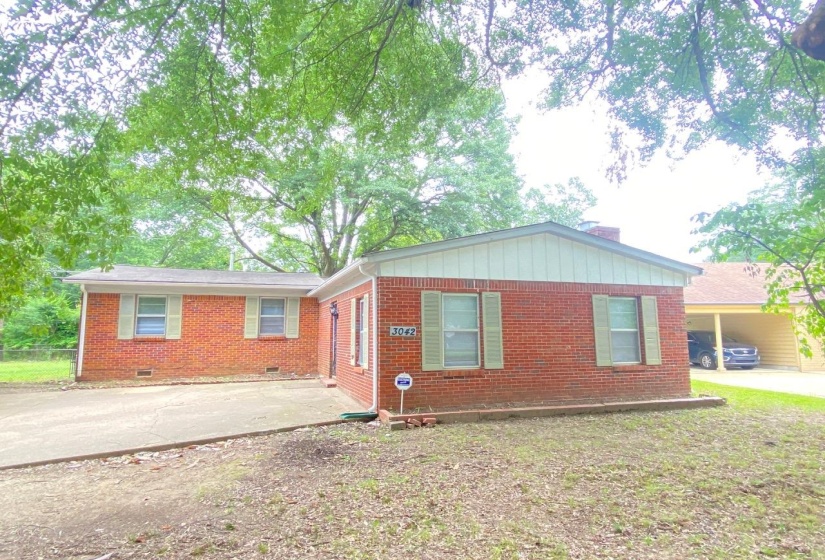 Brick exterior with light-colored shutters and a covered carport