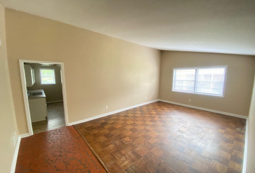 Spacious room featuring wood-finish parquet flooring, neutral wall paint, and white baseboards