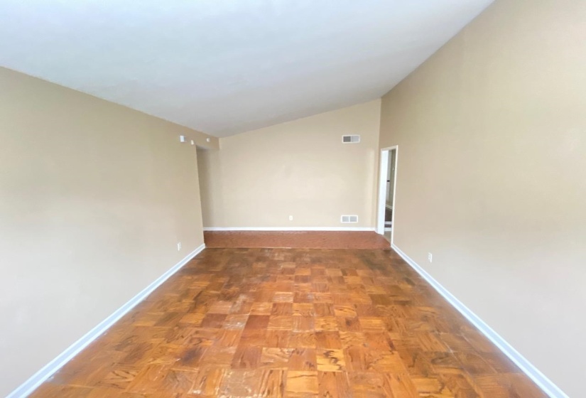 Spacious room featuring wood-finish parquet flooring and neutral wall paint