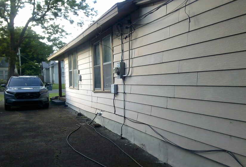 Exterior siding with multiple windows and exposed electrical conduits