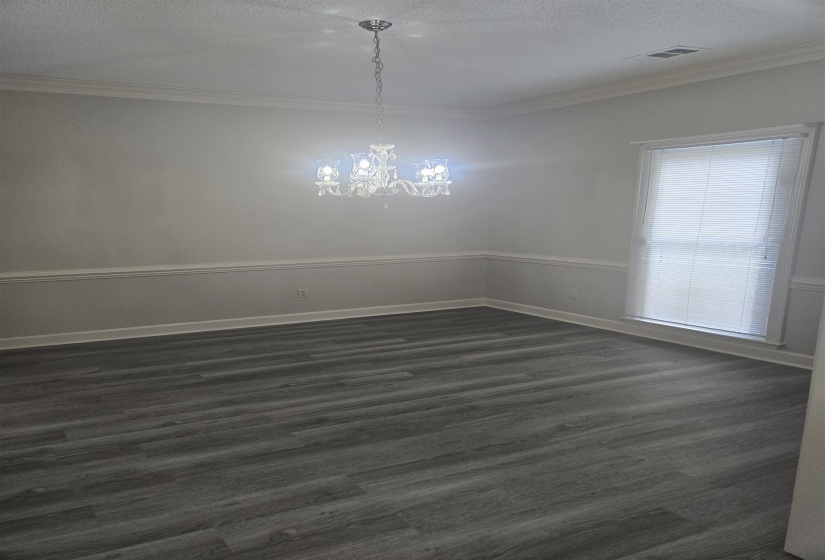 Spacious room featuring wood-finish flooring, a contemporary chandelier, crown molding, chair rail molding, and a window with blinds