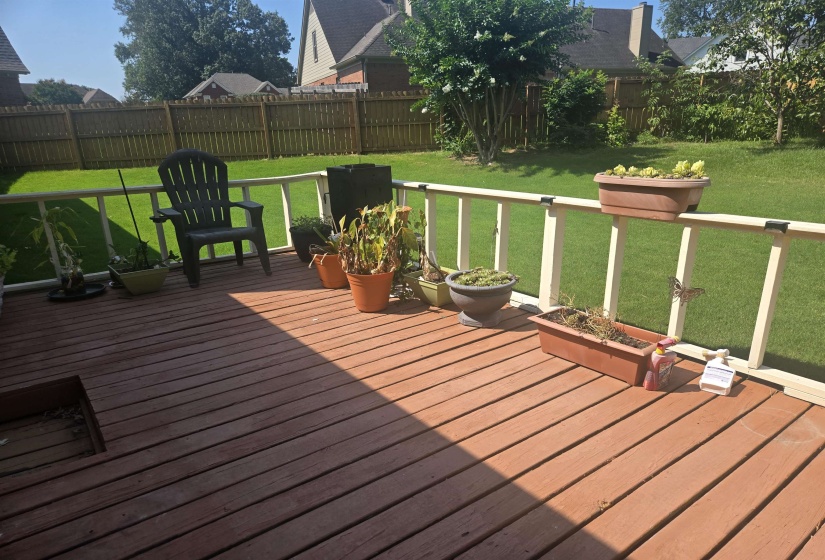 Expansive wood deck with a perimeter railing overlooking a green lawn, featuring a wood privacy fence