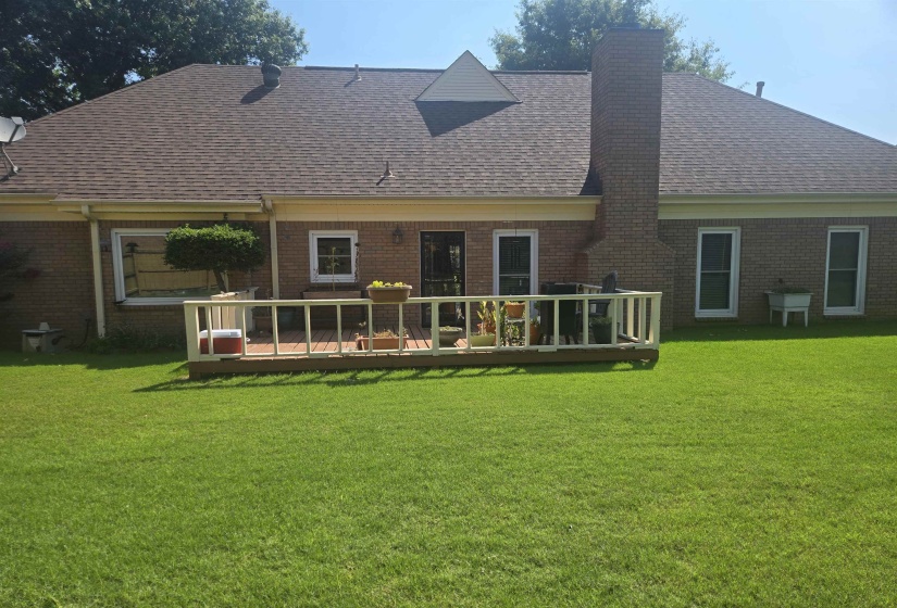 Expansive grassy yard featuring a wood deck with a white railing