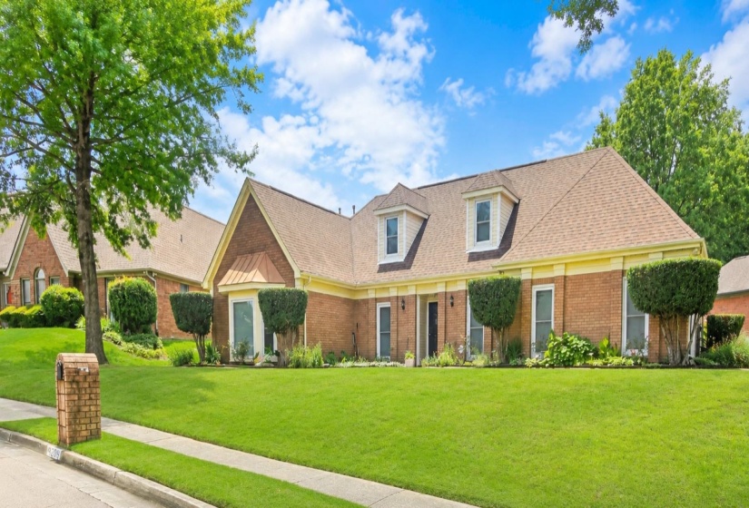 Brick exterior with dormer windows and a shingle roof