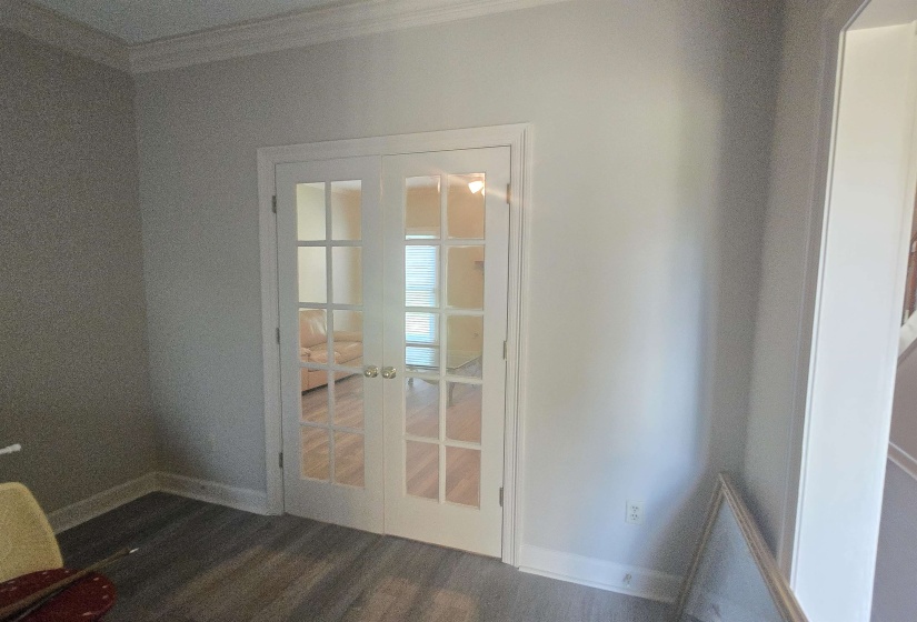 White French doors with clear glass panels open into a room featuring wood-finish flooring