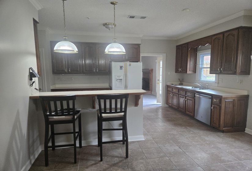 Kitchen featuring wood cabinetry, light-toned countertops, and tile flooring