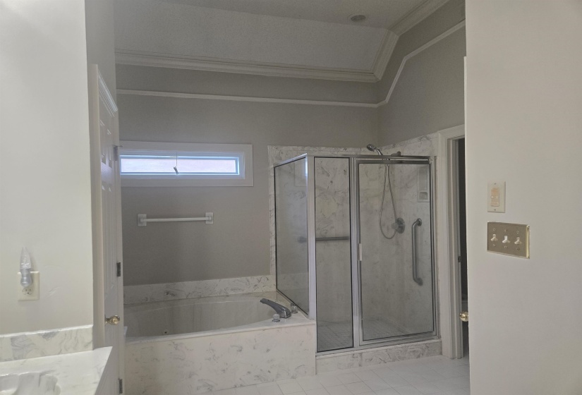 Bathroom featuring a built-in soaking tub with a tiled surround, an enclosed shower with a glass door, and a horizontal transom window
