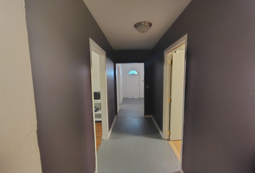 Hallway featuring painted walls, light wood-finish flooring, a flush-mount ceiling light fixture, and visible doorways