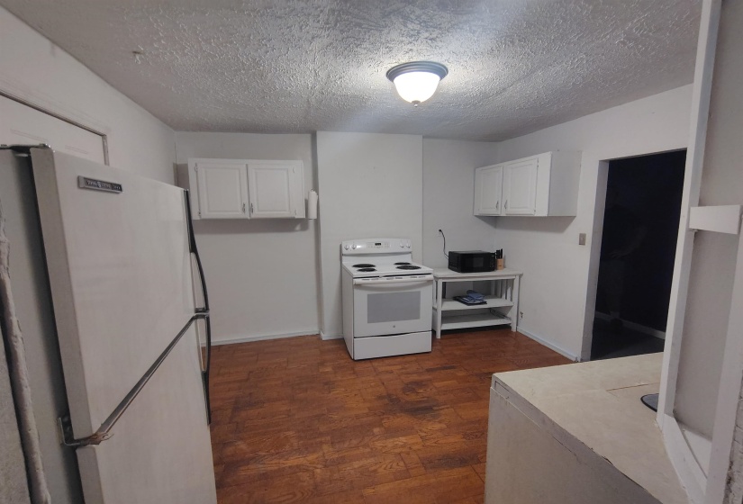 Kitchen featuring wood-finish flooring, white cabinetry, a white electric range, and a white refrigerator