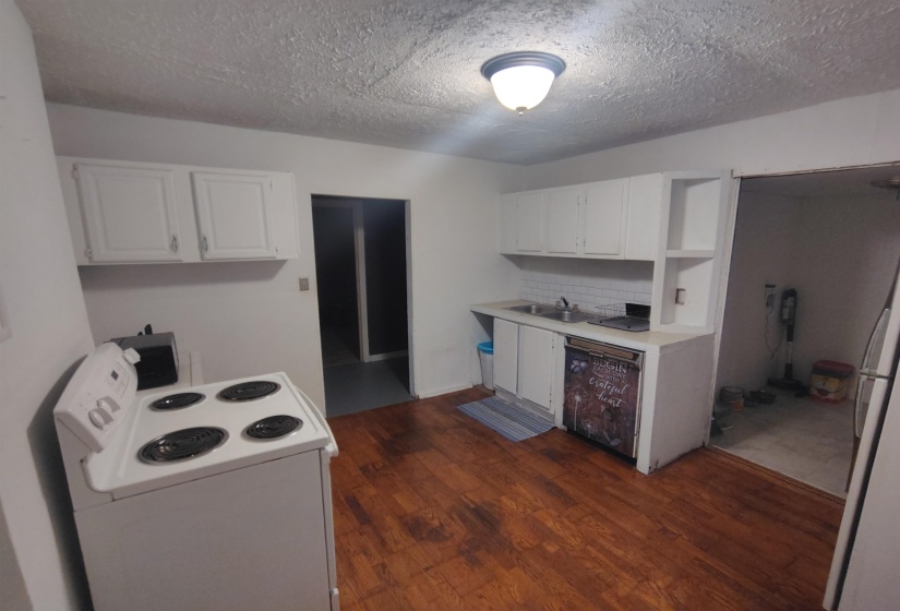 Kitchen featuring wood-finish flooring, white cabinetry, a white electric range, and a drop-in sink with a white subway tile backsplash