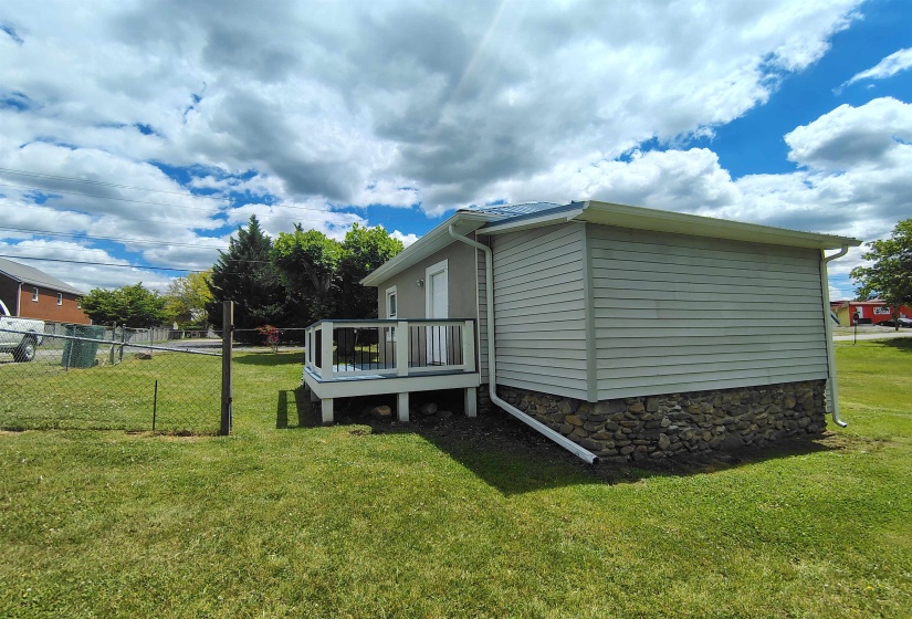 Rear exterior featuring light-colored siding, a stone foundation, and a raised composite deck with white railings