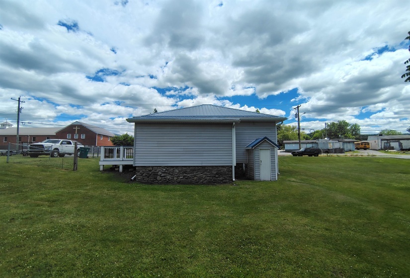 Exterior featuring light gray siding, a blue metal roof, and a stone foundation