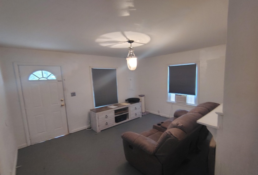 Entry room with a white arched transom door, two windows with dark roller shades, and a ceiling-mounted light fixture